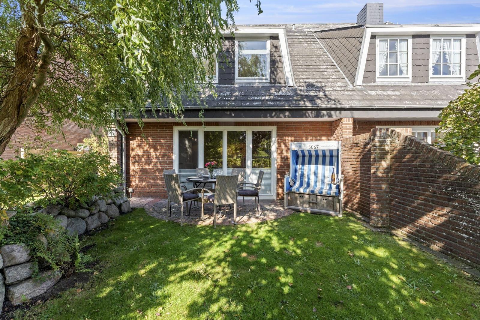 Haus mit Garten, Terrasse und Strandkorb. Holzveranda mit Tisch und Stühlen.
