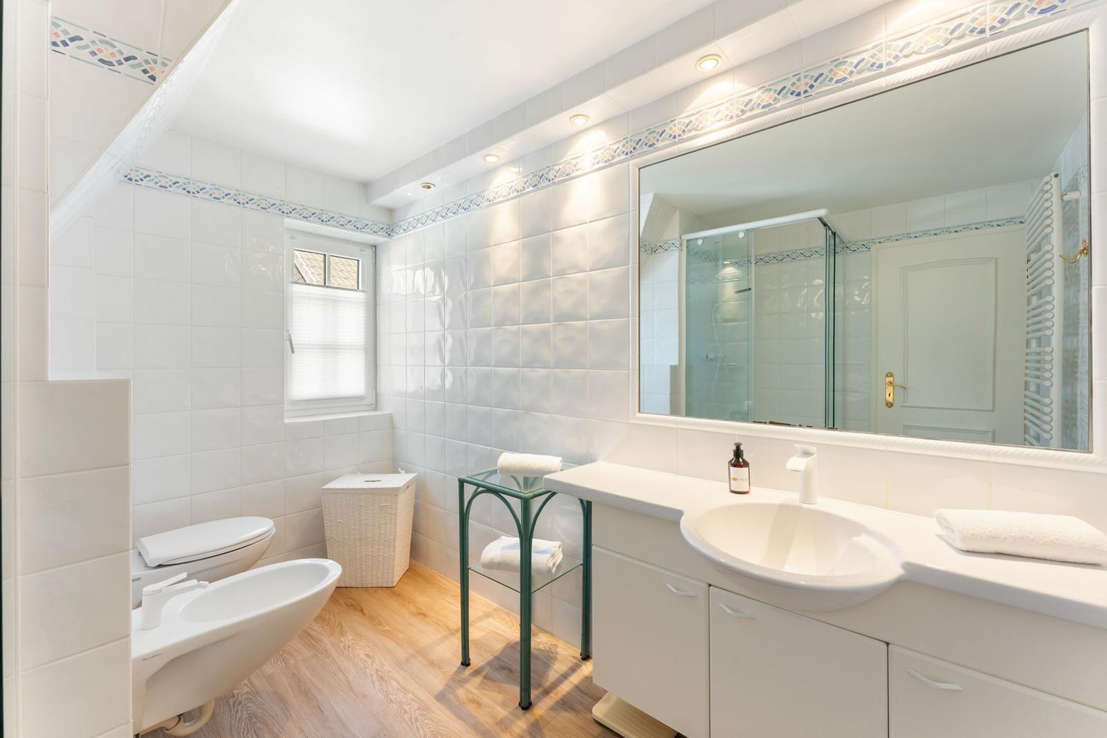 Badezimmer mit Waschbecken, Spiegel, Toilette und Dusche