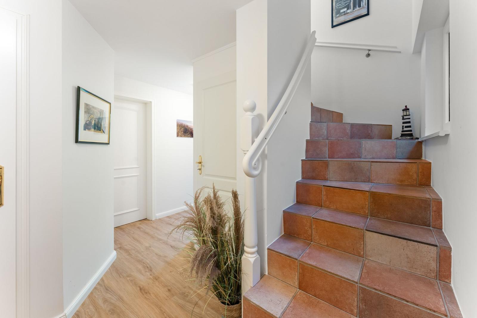 Haus mit Treppenhaus, Terrakottatreppe und Pflanze an der Wand.