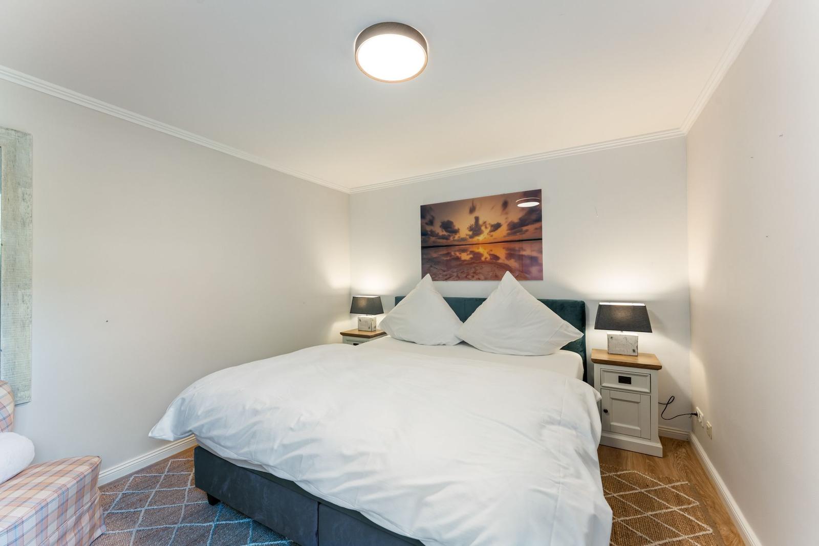 Schlafzimmer mit Doppelbett, zwei Nachttischen und Wandbild.