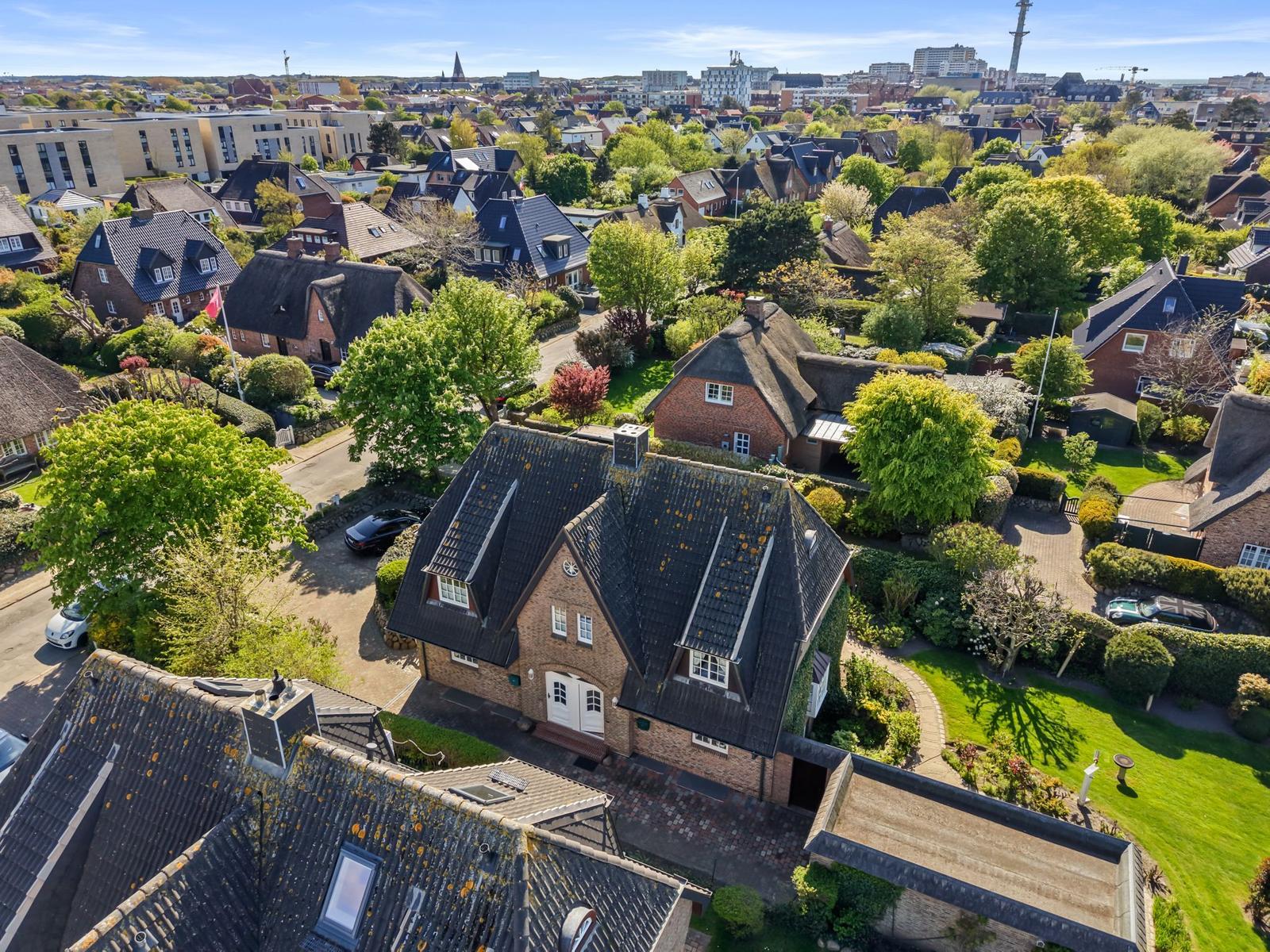 Haus mit Dach und Garten in einer städtischen Umgebung mit Bäumen und Nachbarhäusern.