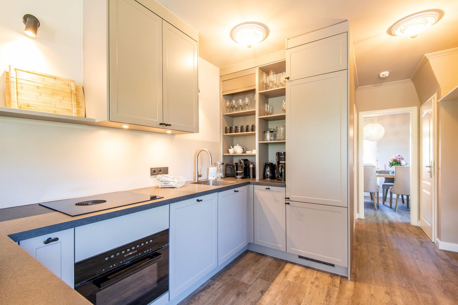 Küche mit hellen Schränken, Arbeitsplatte und Blick in Esszimmer.