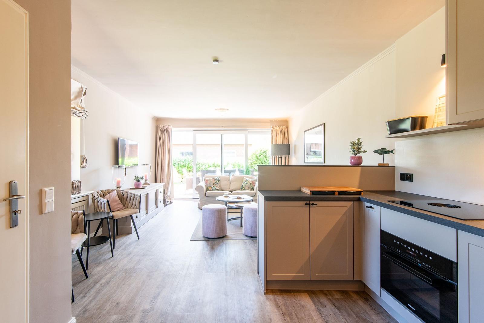 Küche mit Essbereich und Wohnzimmer mit Sofa und Terrasse.