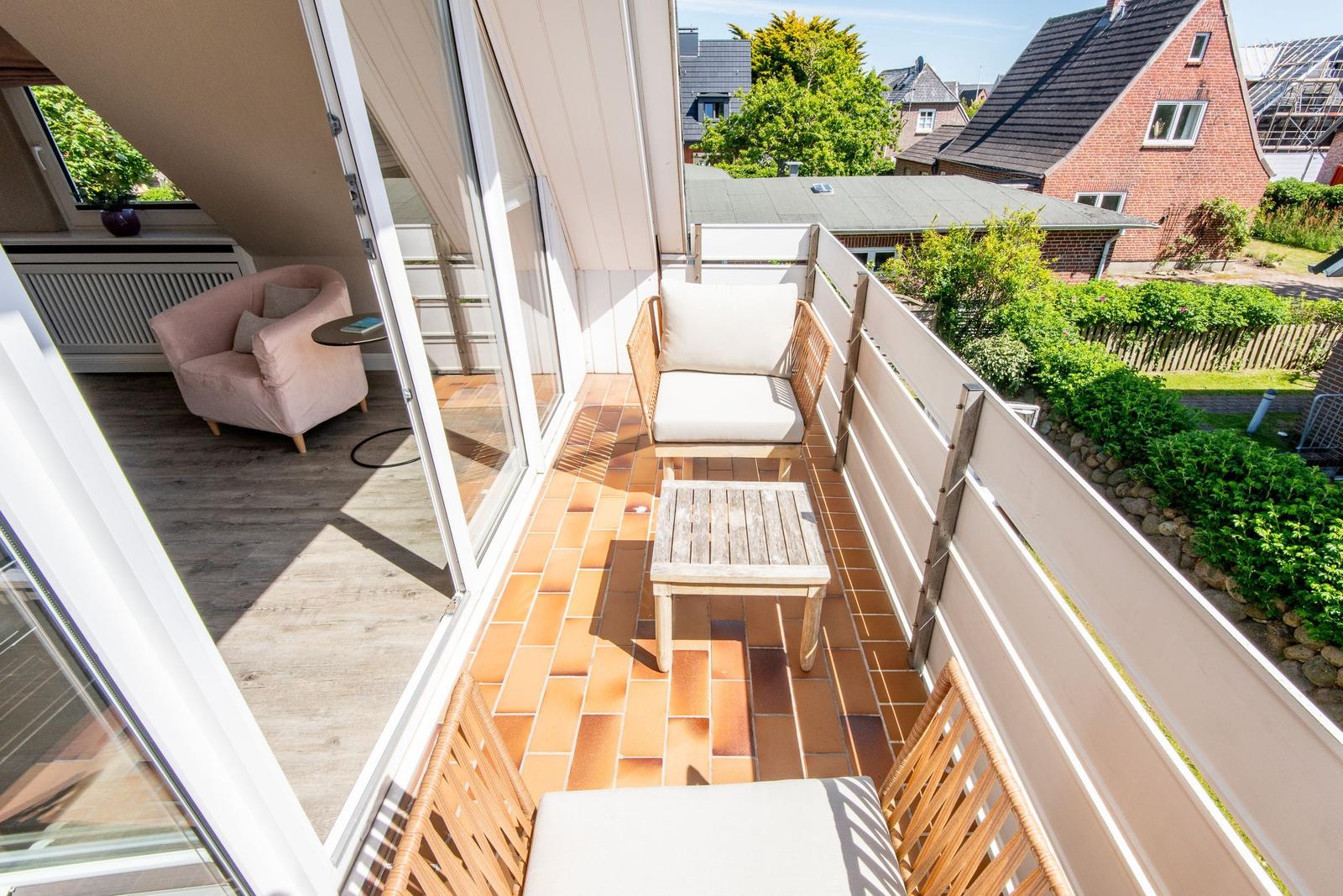 Terrasse mit Sitzgelegenheiten und Blick auf Garten und Nachbarhäuser.