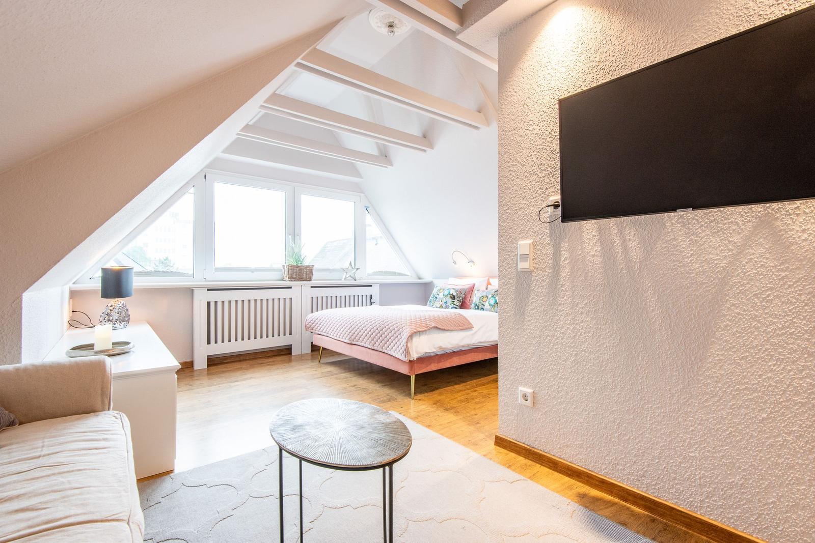 Schlafzimmer mit Dachschrägen, Bett, TV und Fenster