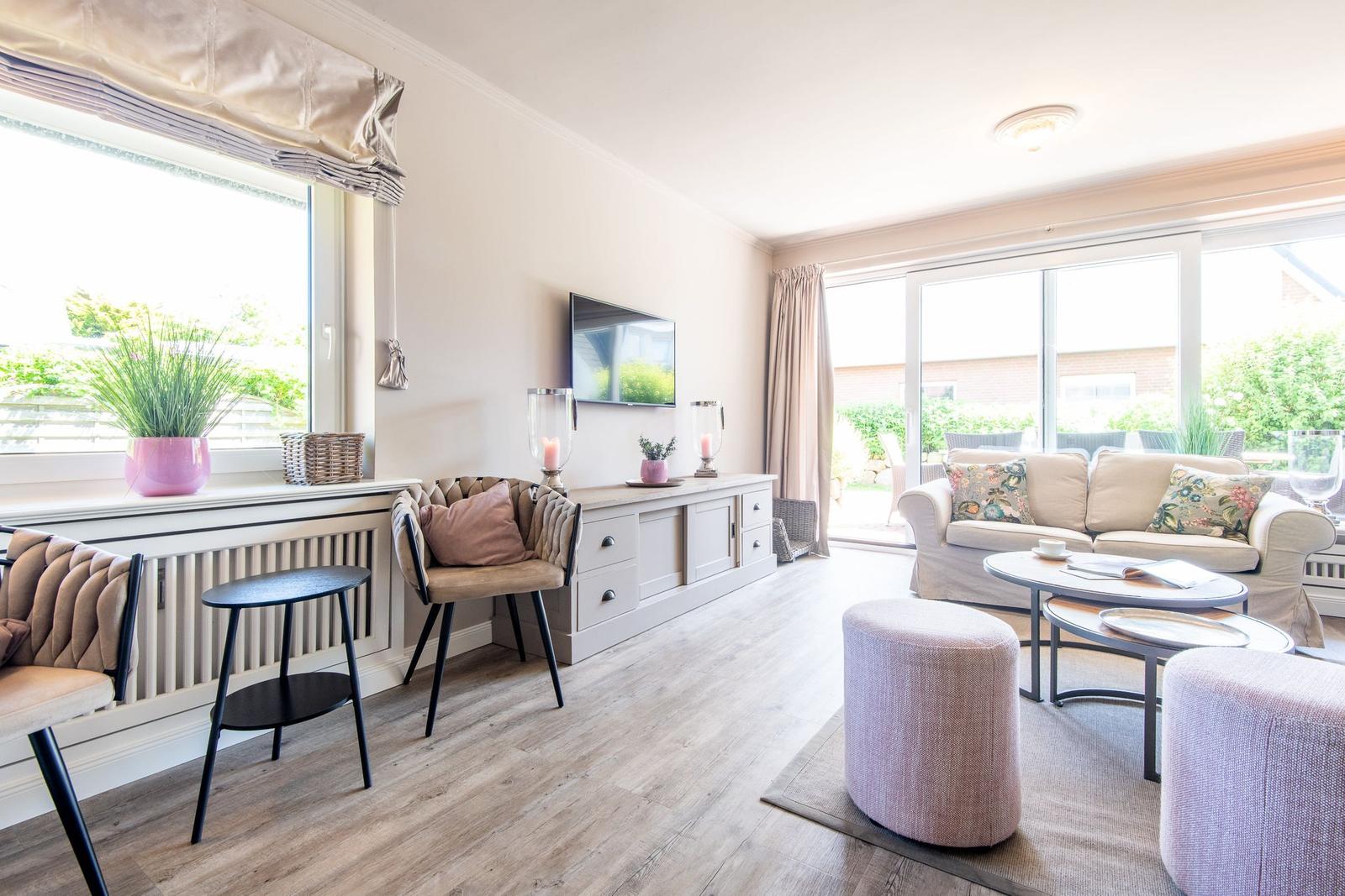 Wohnzimmer mit Sofa, TV und großem Fenster. Holzboden und moderne Möbel.