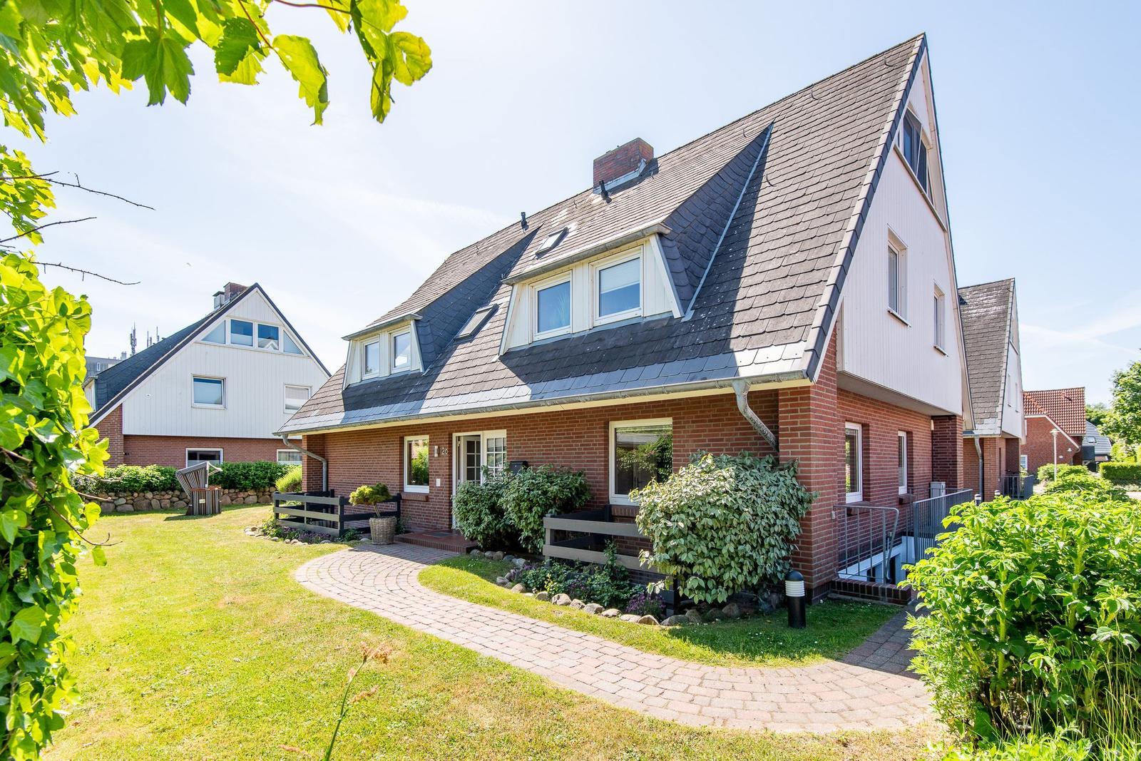Ein zweistöckiges Haus mit Dachfenstern und Gartenweg.