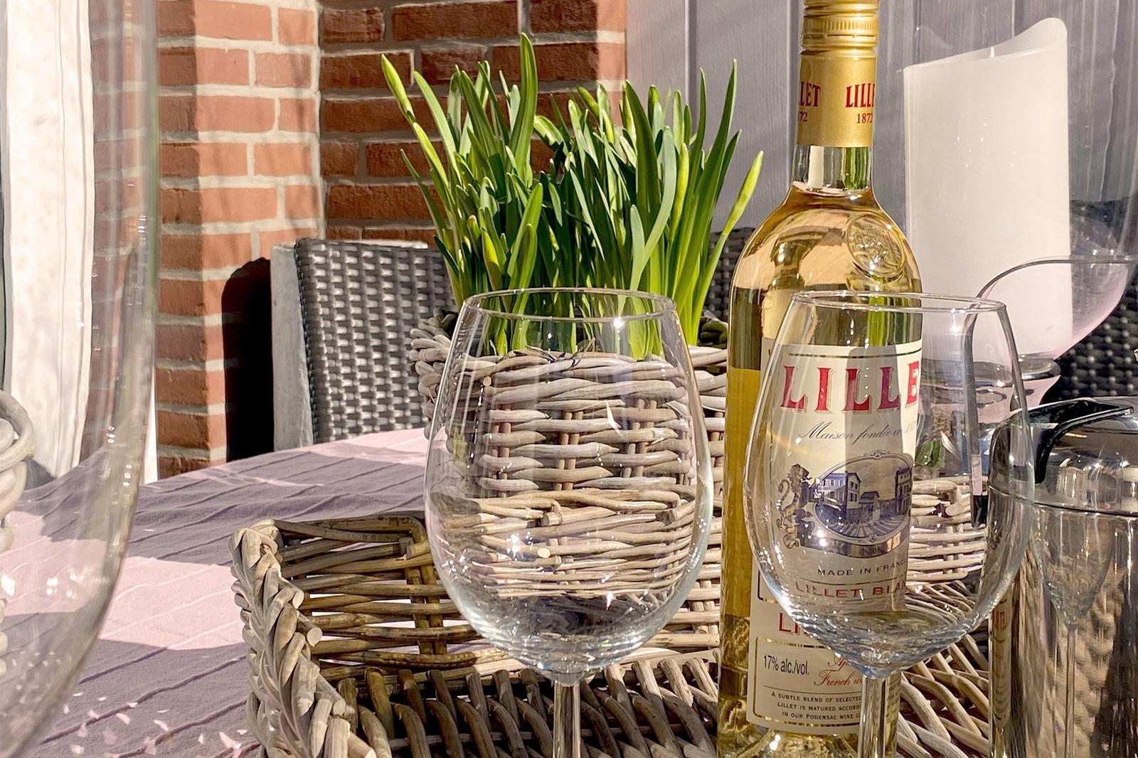 Tisch mit Weinglas, Flasche und Pflanze auf Balkon