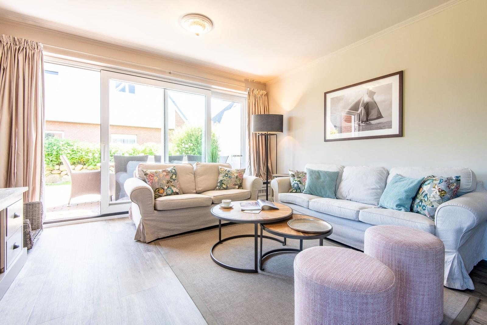 Wohnzimmer mit zwei Sofas, runden Tischen und Blick auf Terrasse.