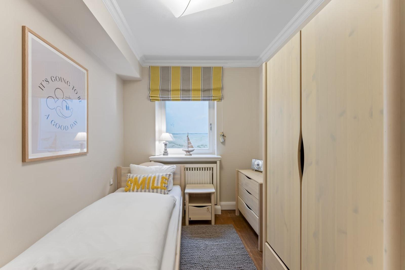 Ein Schlafzimmer mit Bett, Kleiderschrank und Fenster mit Blick aufs Meer.
