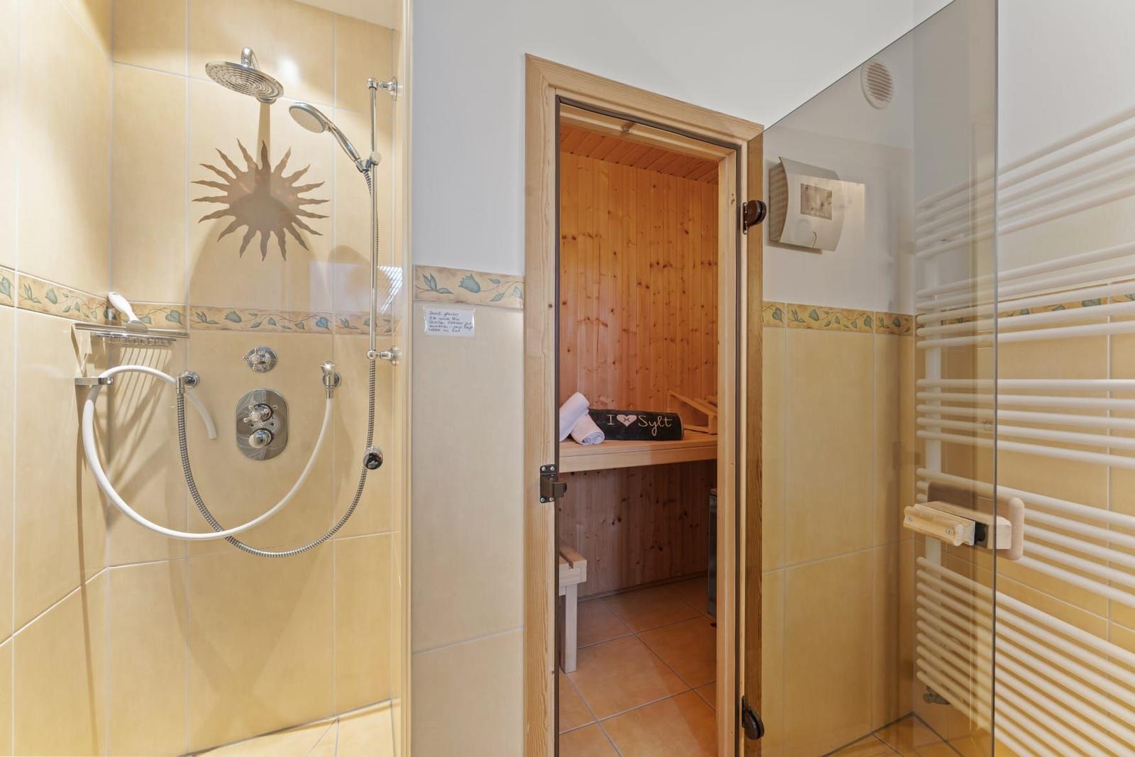 Dusche mit Duschbrause und Sauna mit Holzwand