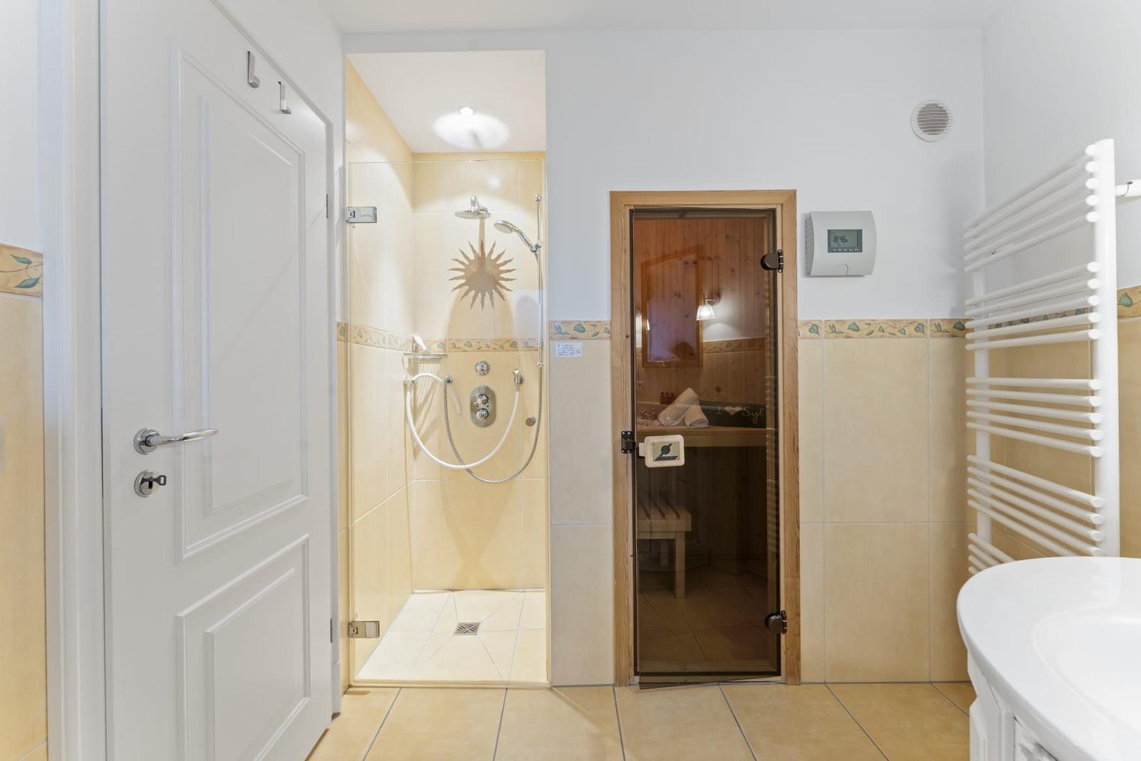 Dusche mit Sonnenmotiv, Sauna und Handtuchwärmer im Badezimmer.