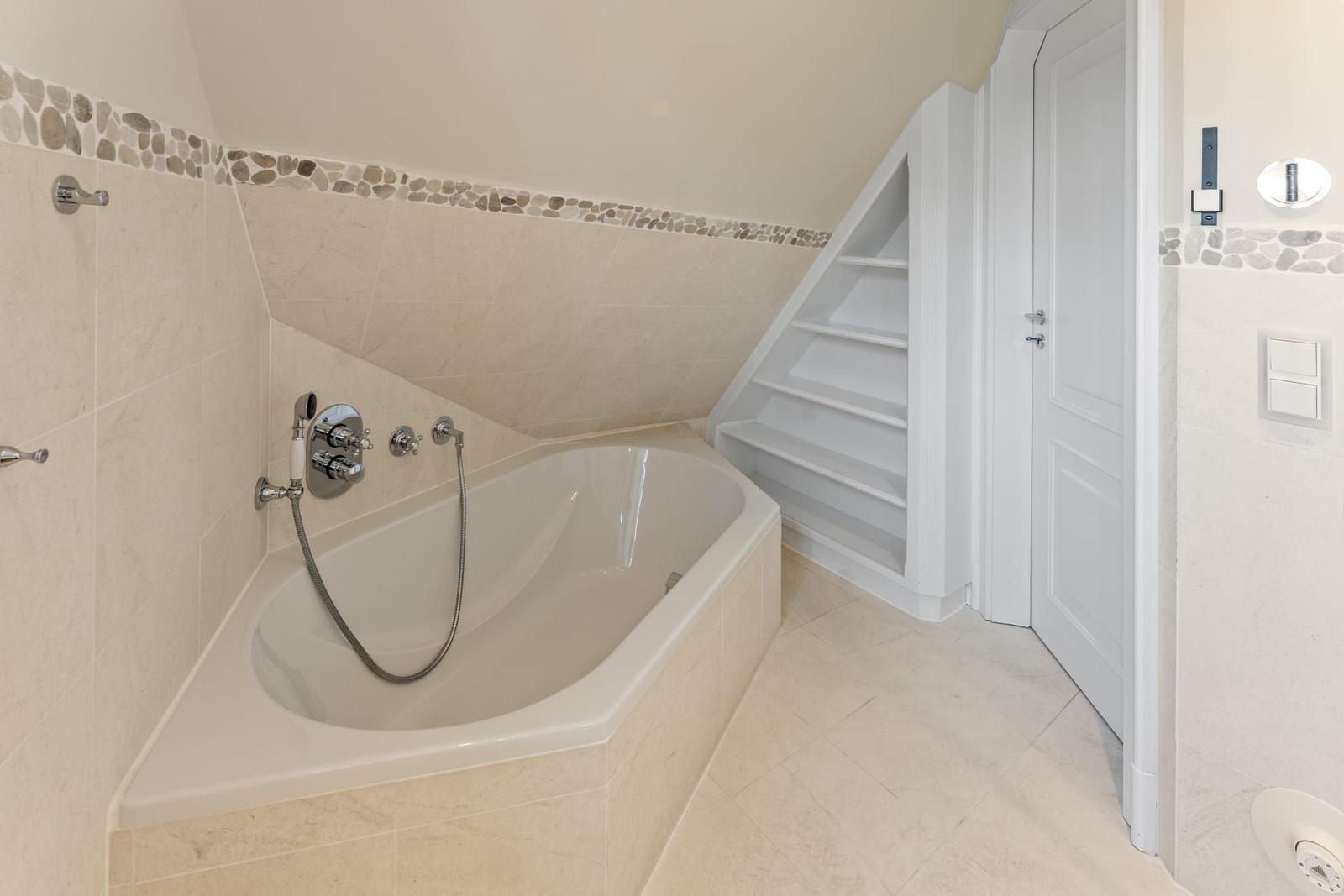 Bad mit Badewanne, Steinverkleidung und eingebautem Regal