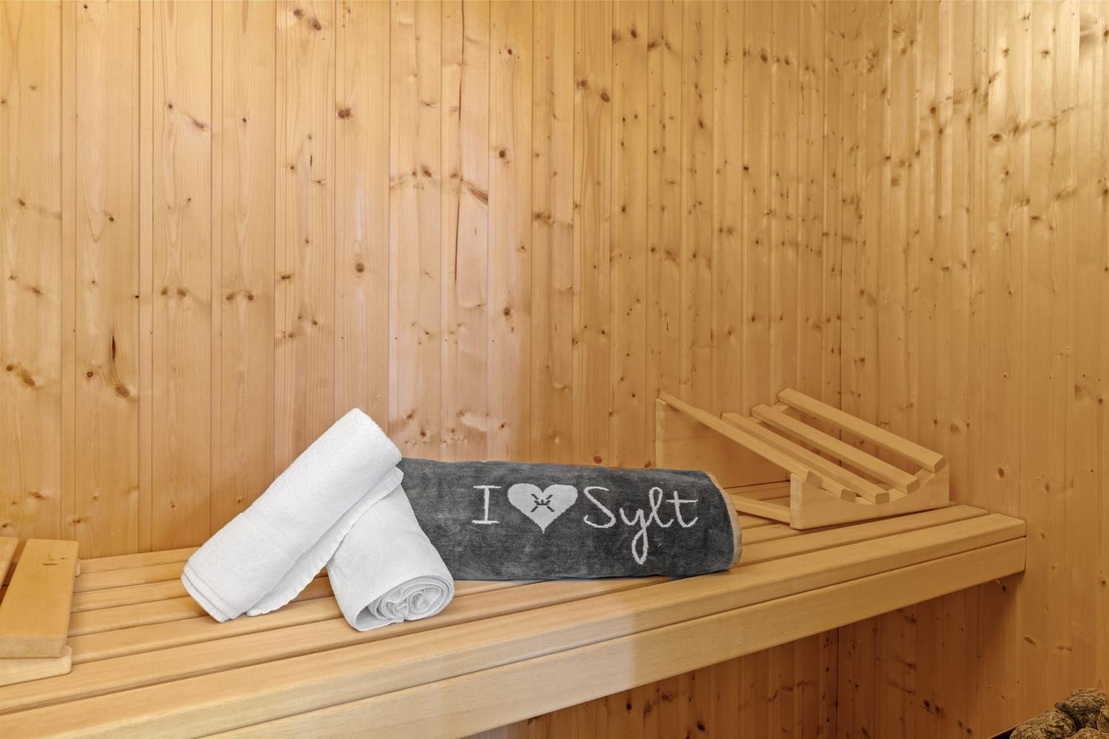 Sauna mit Holzwand und Handtüchern auf der Bank