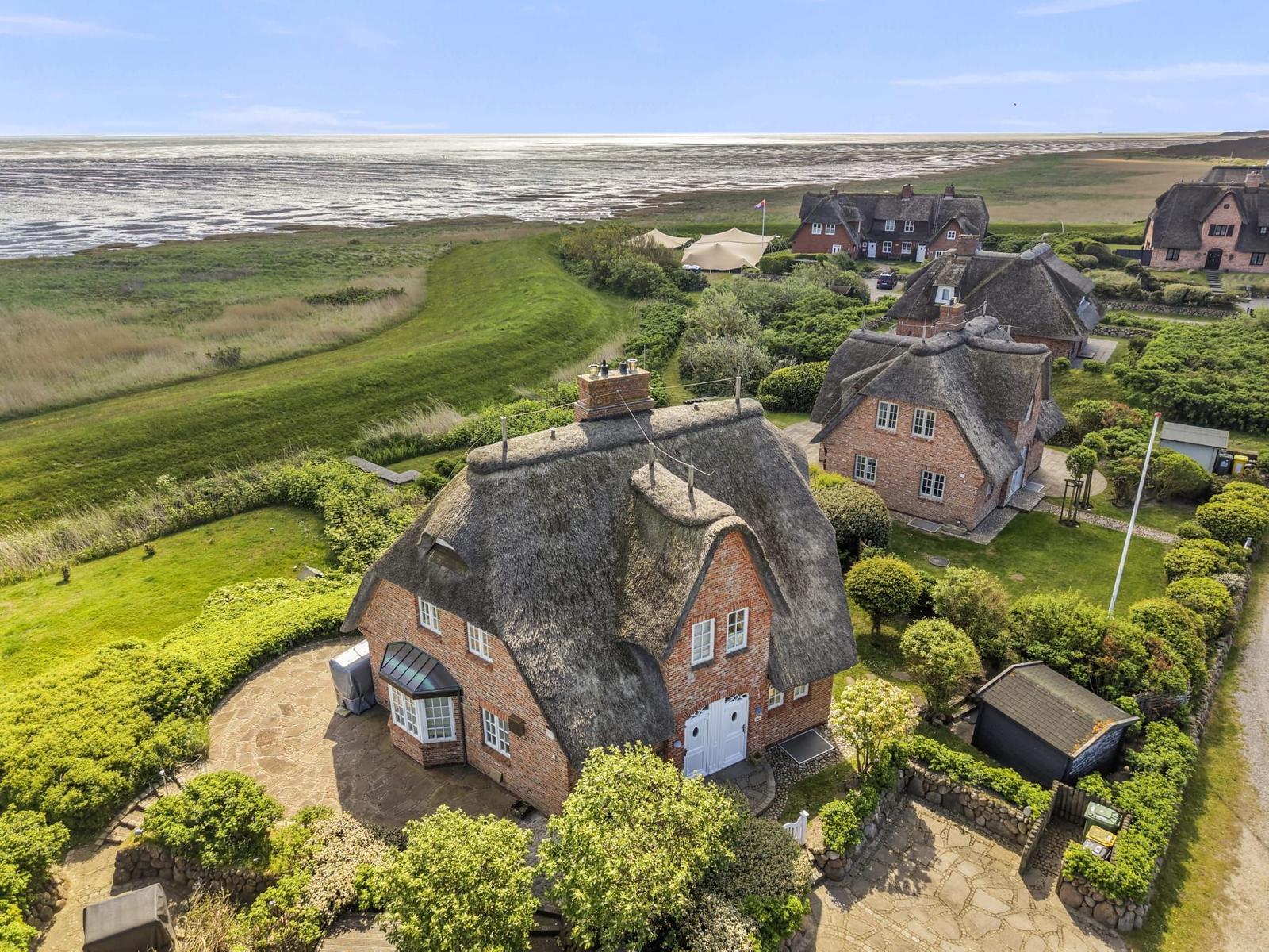 Dorfhaus mit Strohdach und Garten, Blick auf Strand und Watt.