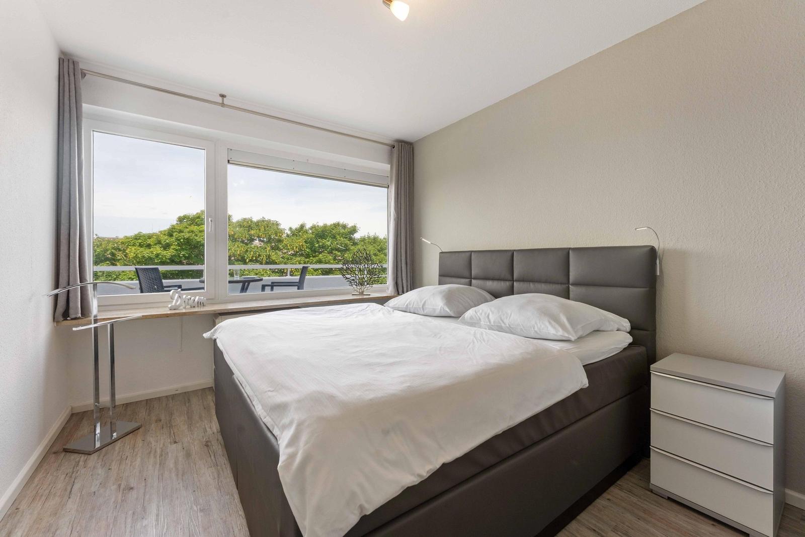 Bedroom with double bed, large window, and balcony view.