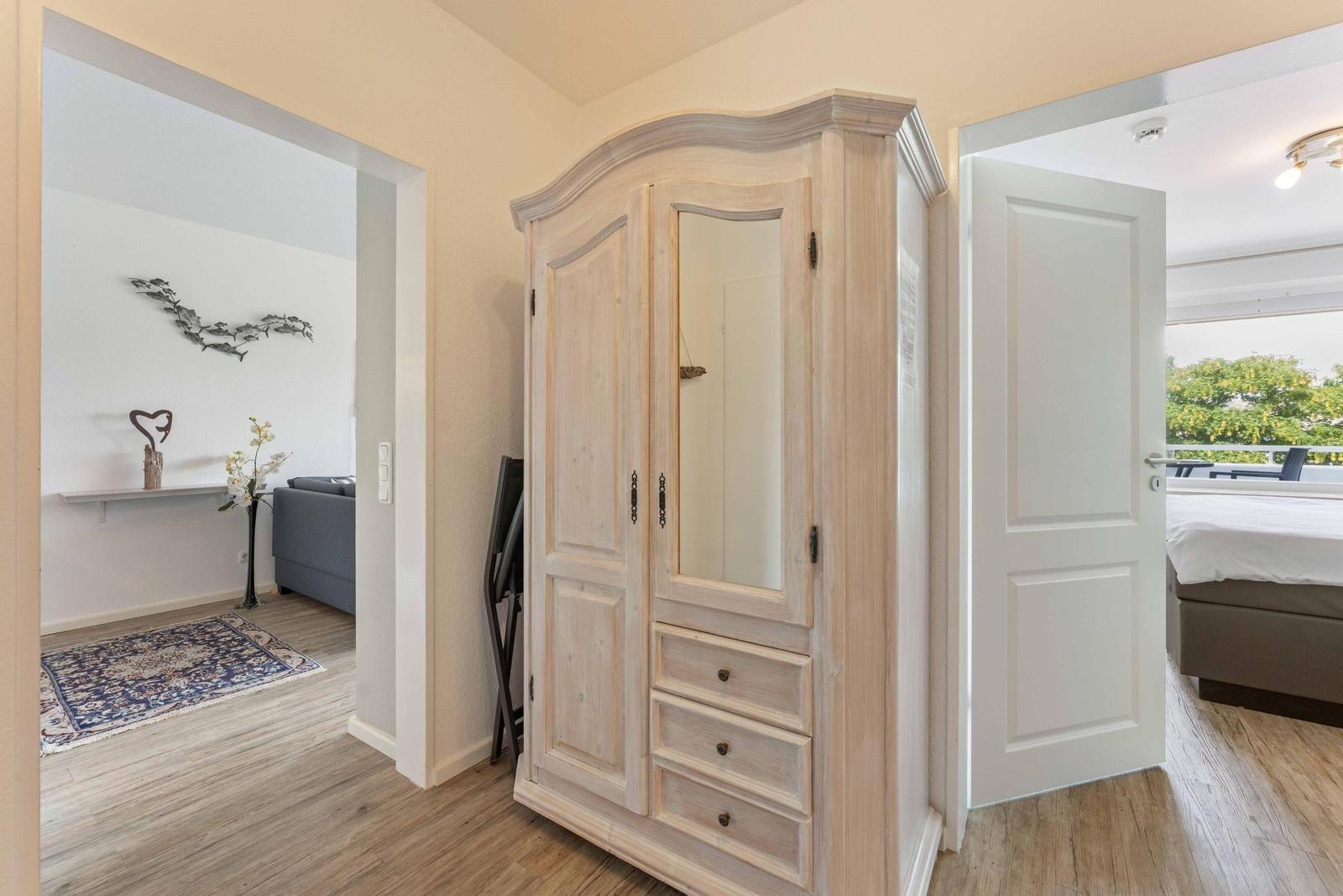 Bedroom with balcony view. Hallway with wardrobe and view into living room.