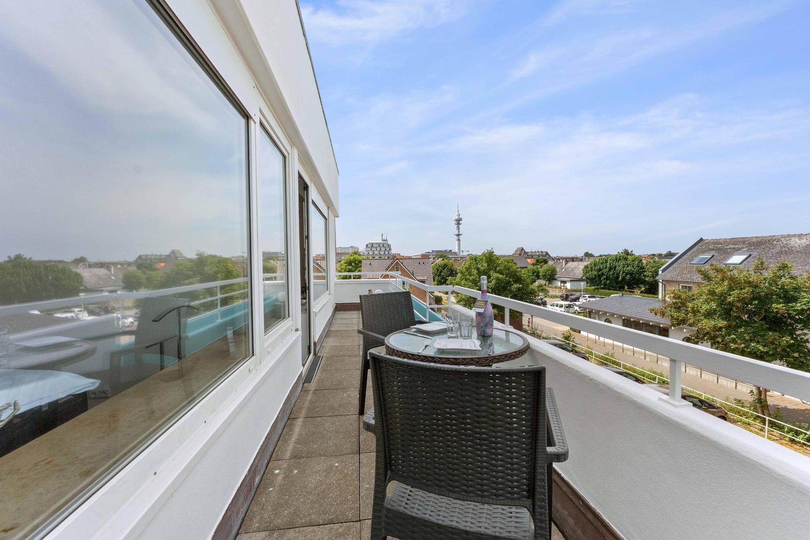 Terrace with table and chairs, view of city and tower.