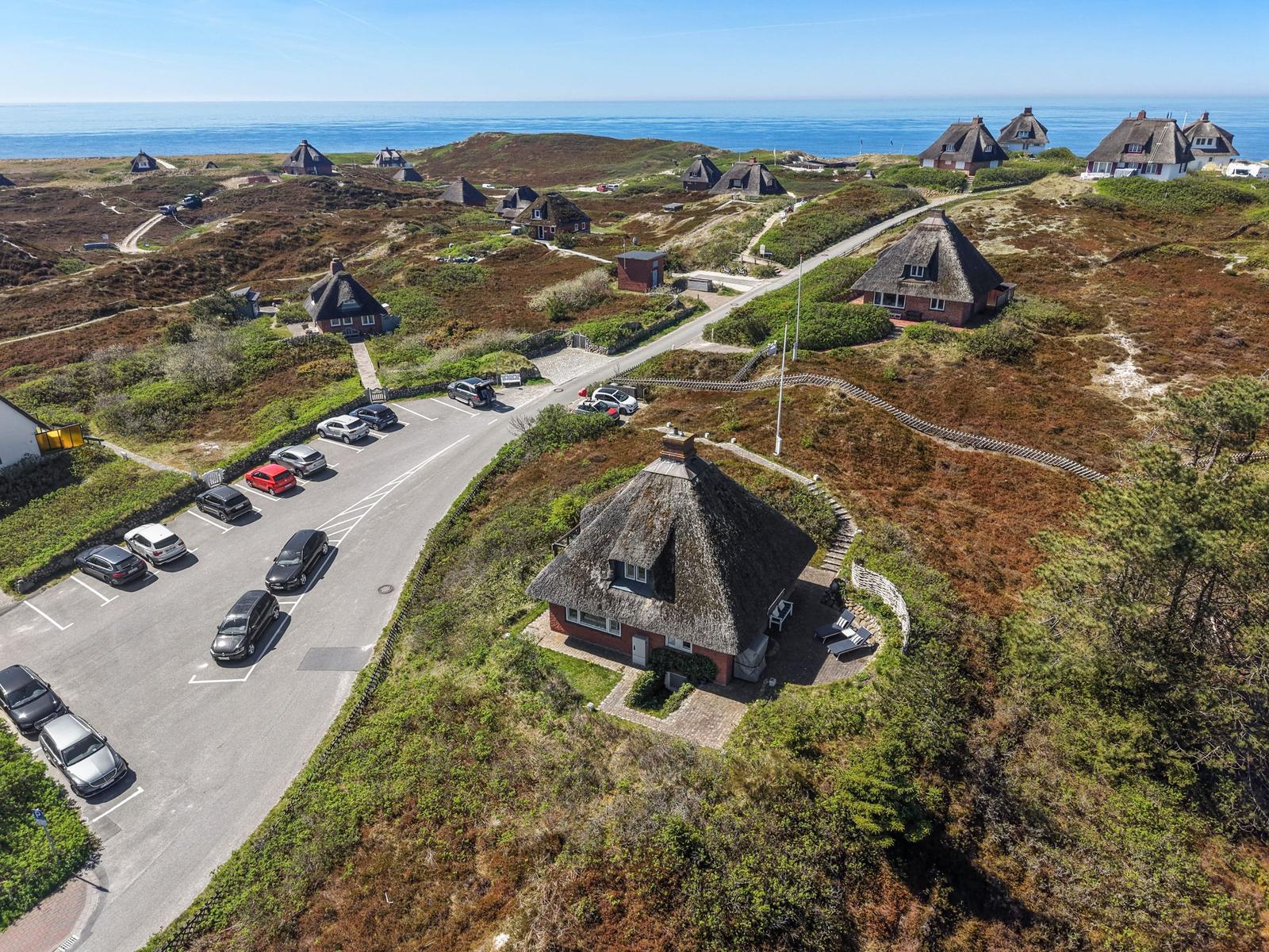 Dorfhäuser mit Strohdächern an der Küste, Parkplatz und Strandweg