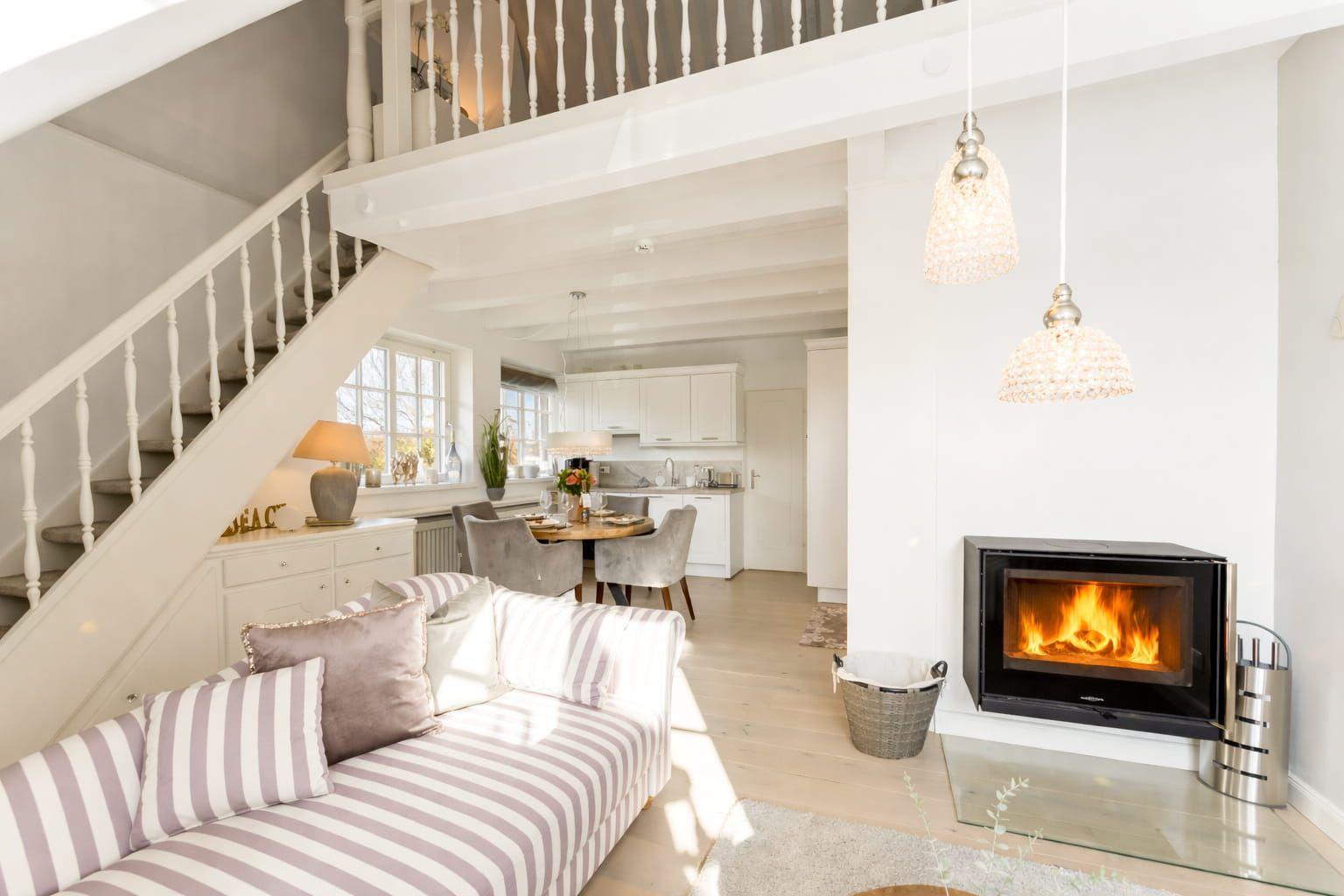 Living room with sofa, fireplace, and staircase to a gallery