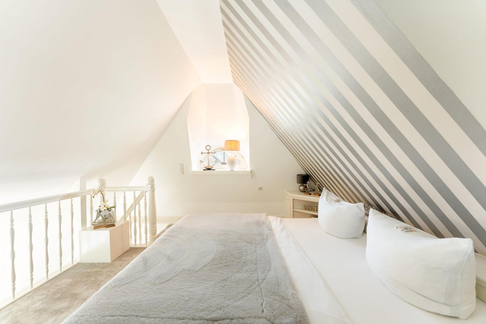 Bedroom with sloped ceiling, bed, nightstand, and window.