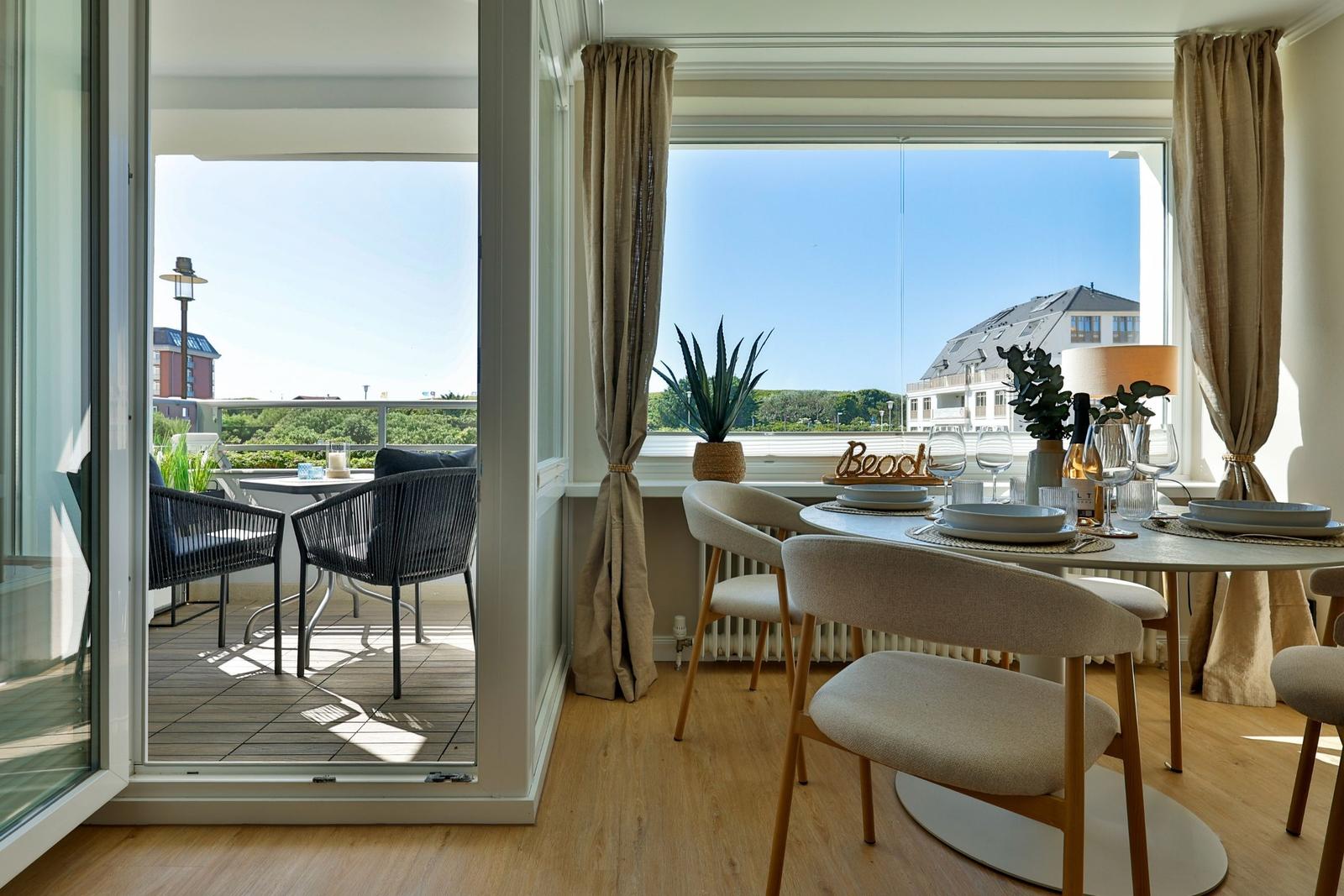 Essbereich mit Tisch und Stühlen, Blick auf Balkon und Strand.