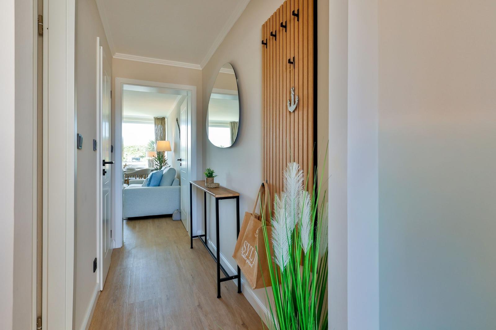 Hausflur mit Holzboden, Spiegel und Garderobe mit Haken.