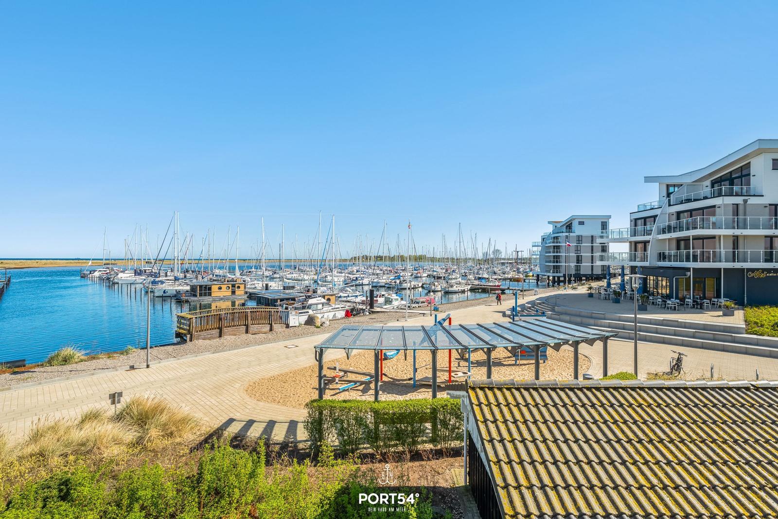 Hafen mit Booten, Spielplatz und moderne Gebäude am Wasser.