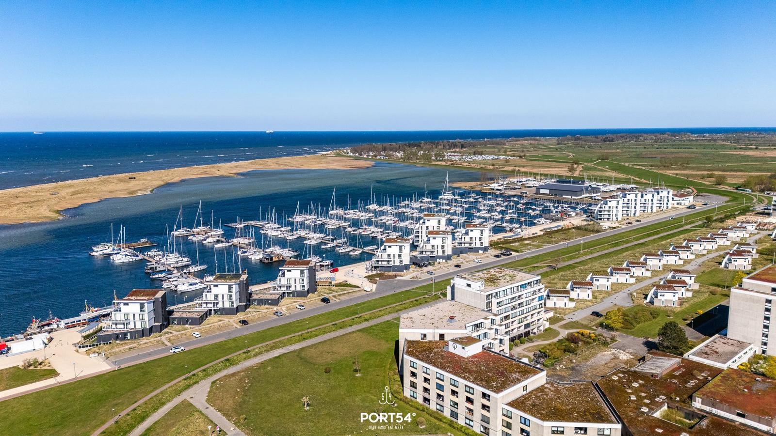 Hafen mit Booten und modernen Wohnhäusern an der Küste.