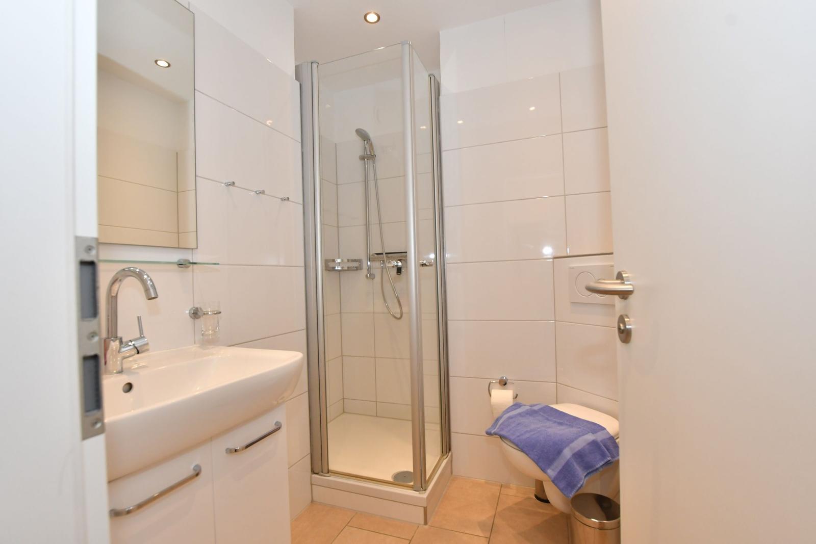 Badezimmer mit Dusche, Waschbecken und Toilette.