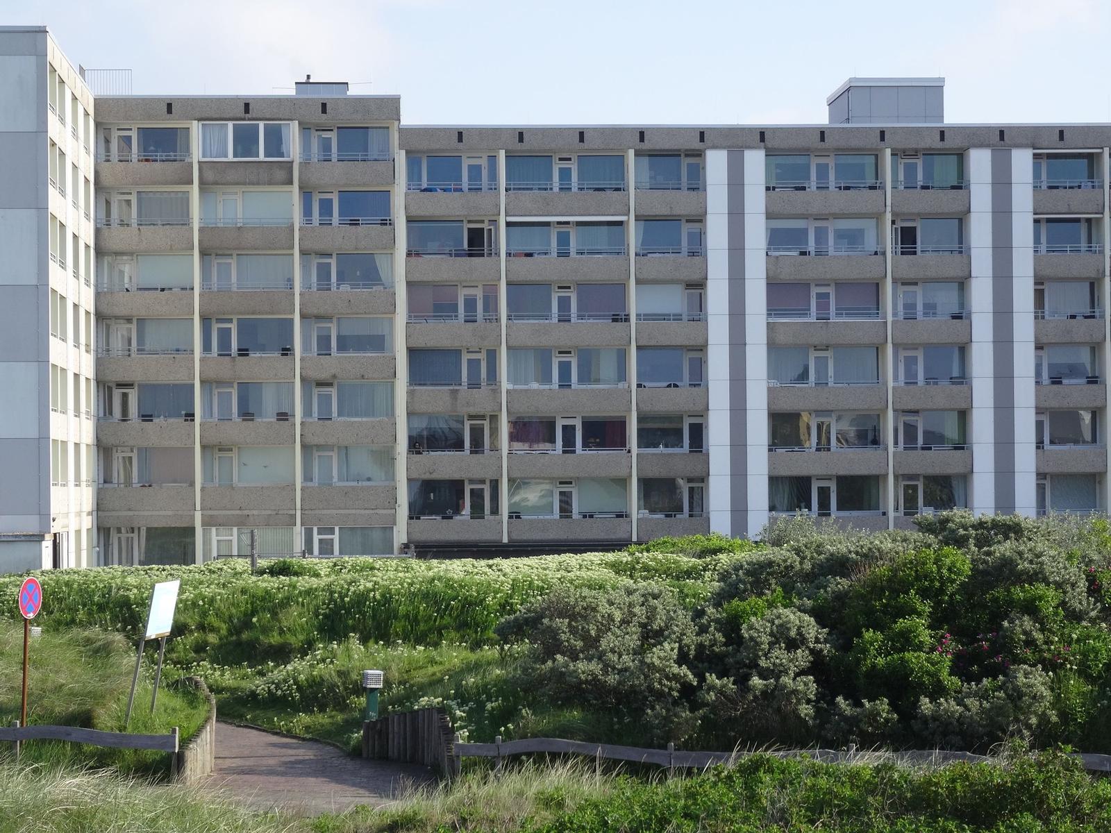 Hochhaus mit Balkonen und Grünflächen im Vordergrund.