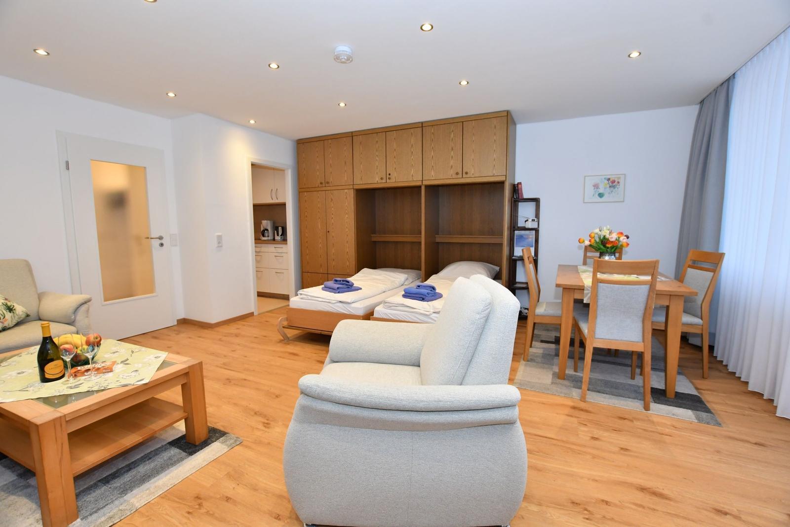 Wohnraum mit Schlafcouch, Esstisch und Küchenbereich. Holzboden und Holzmöbel.