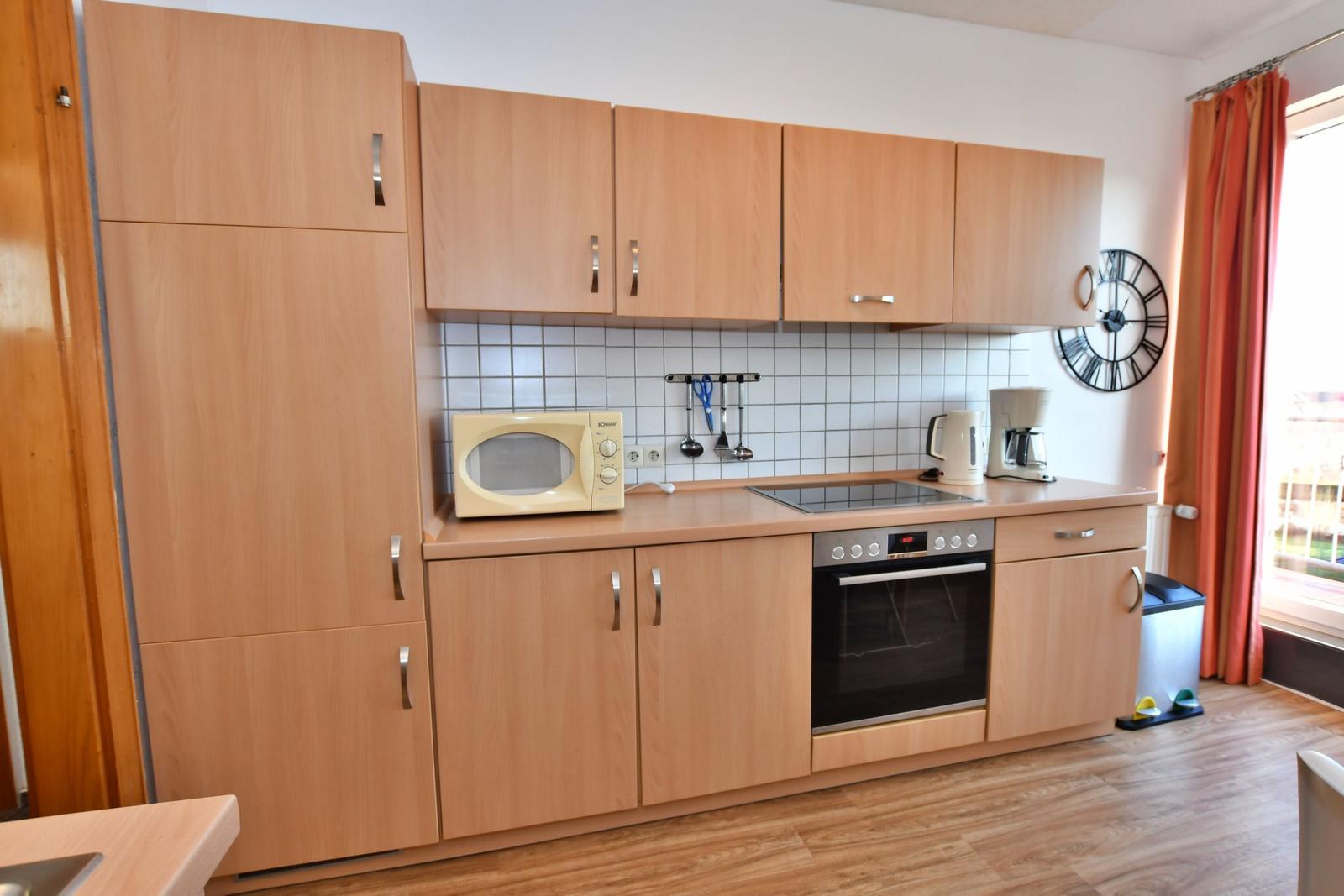 Küche mit Holzschränken, Herd, Mikrowelle und Kaffeemaschine.