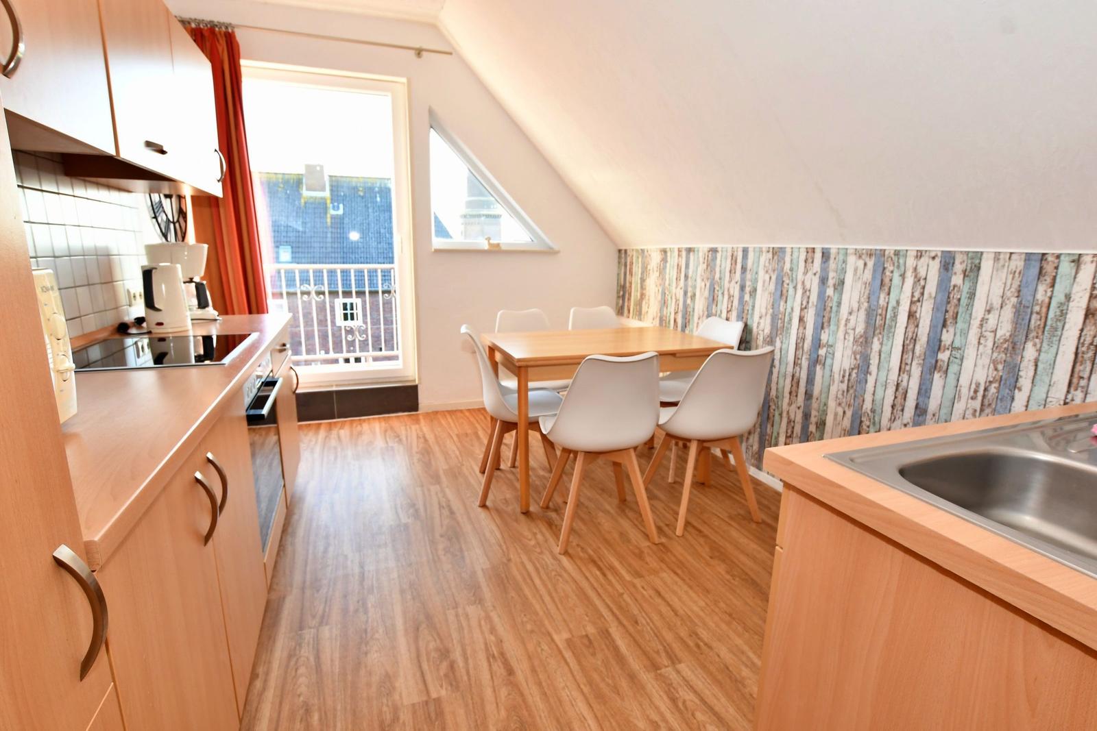 Küche mit Essbereich, Holzboden und Fenster zum Balkon.
