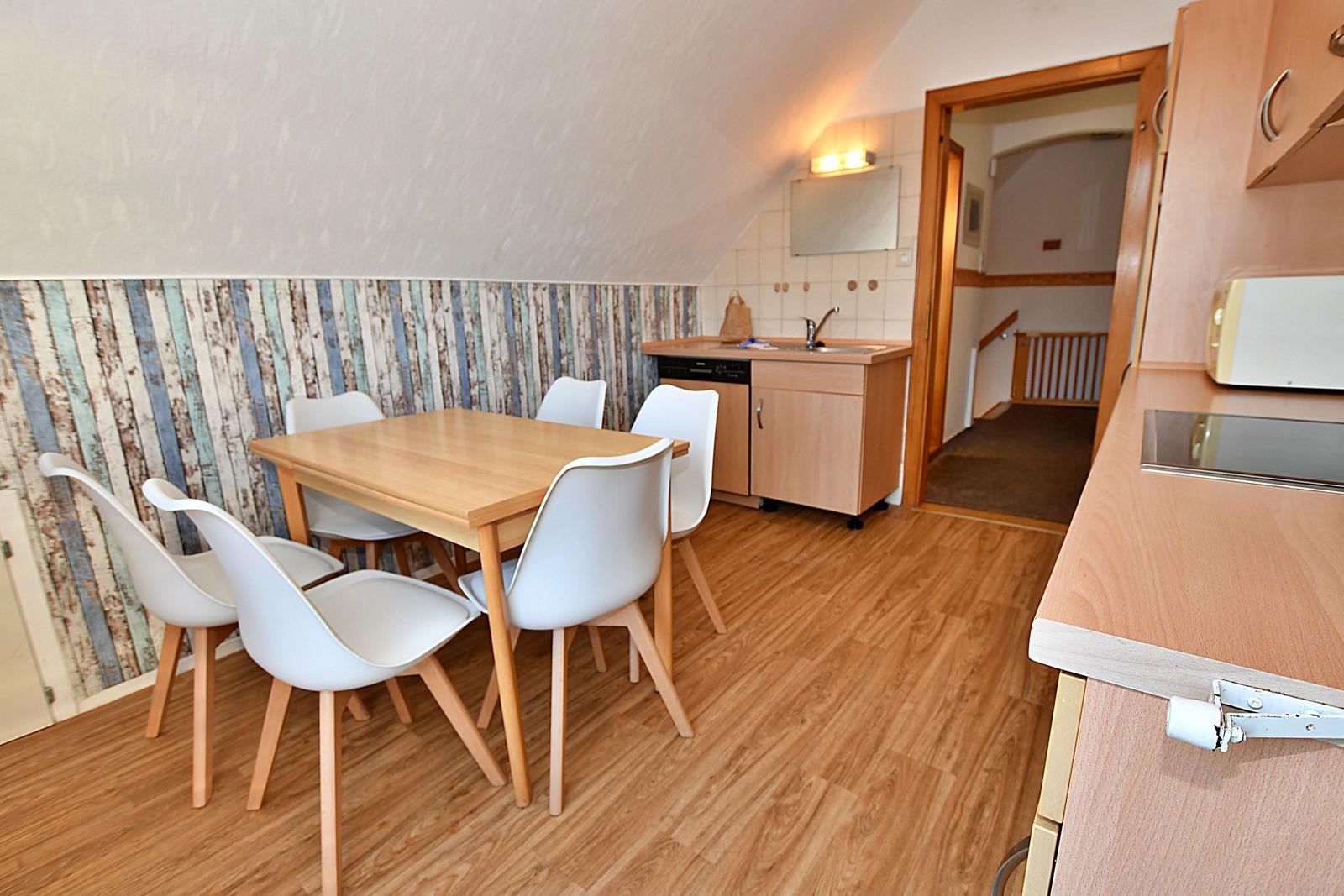 Essbereich mit Tisch und Stühlen, Küchenzeile und angrenzender Wohnung.