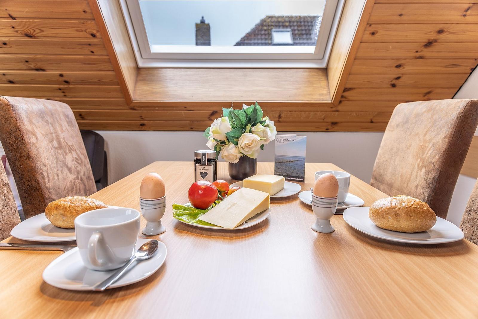 Frühstückstablett mit Käse, Eiern und Brot unter einem Dachfenster mit Holzdecke.