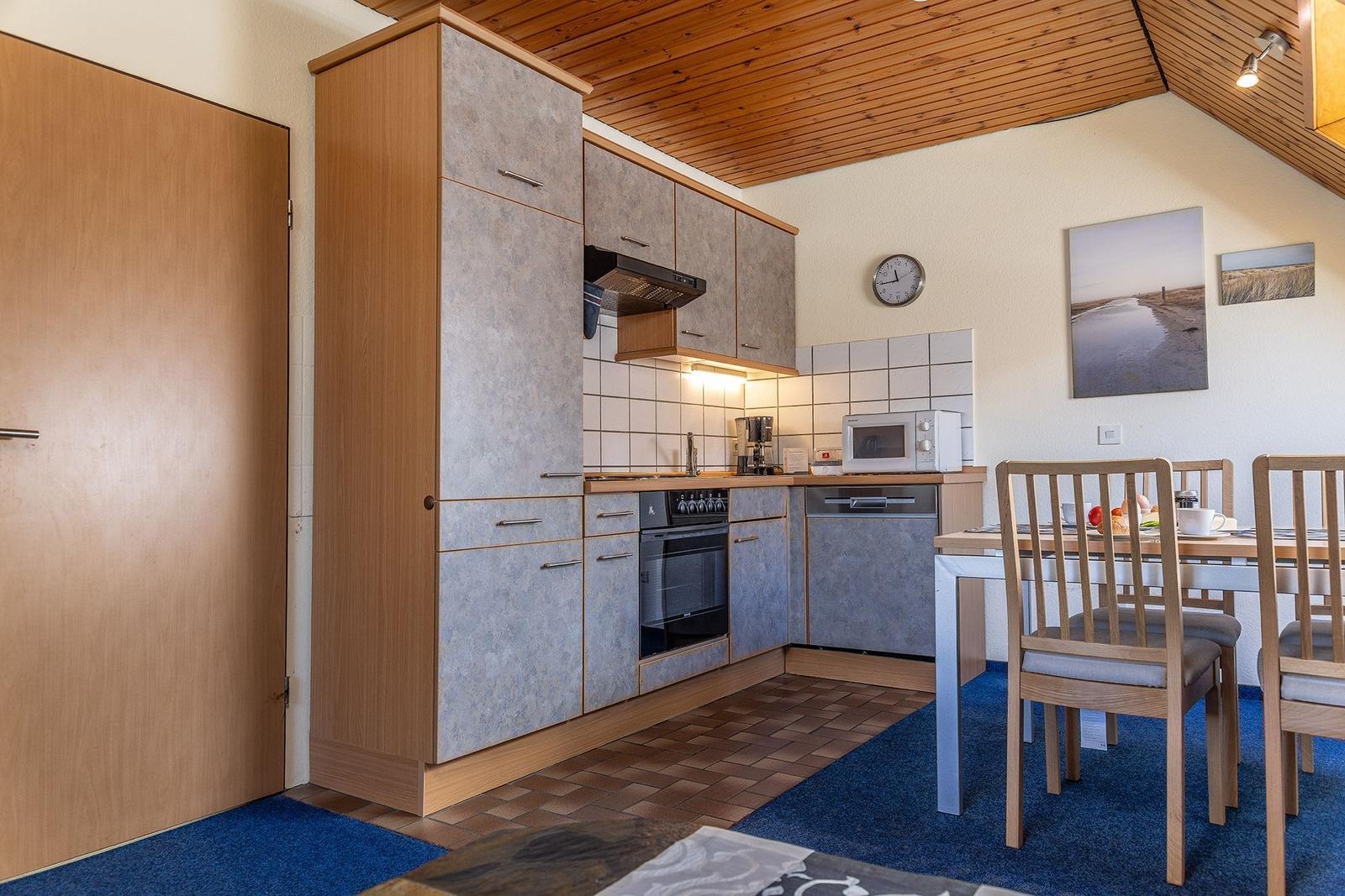 Küche mit Essbereich, Holzdecke, Küchenschränke und Tisch mit Stühlen.