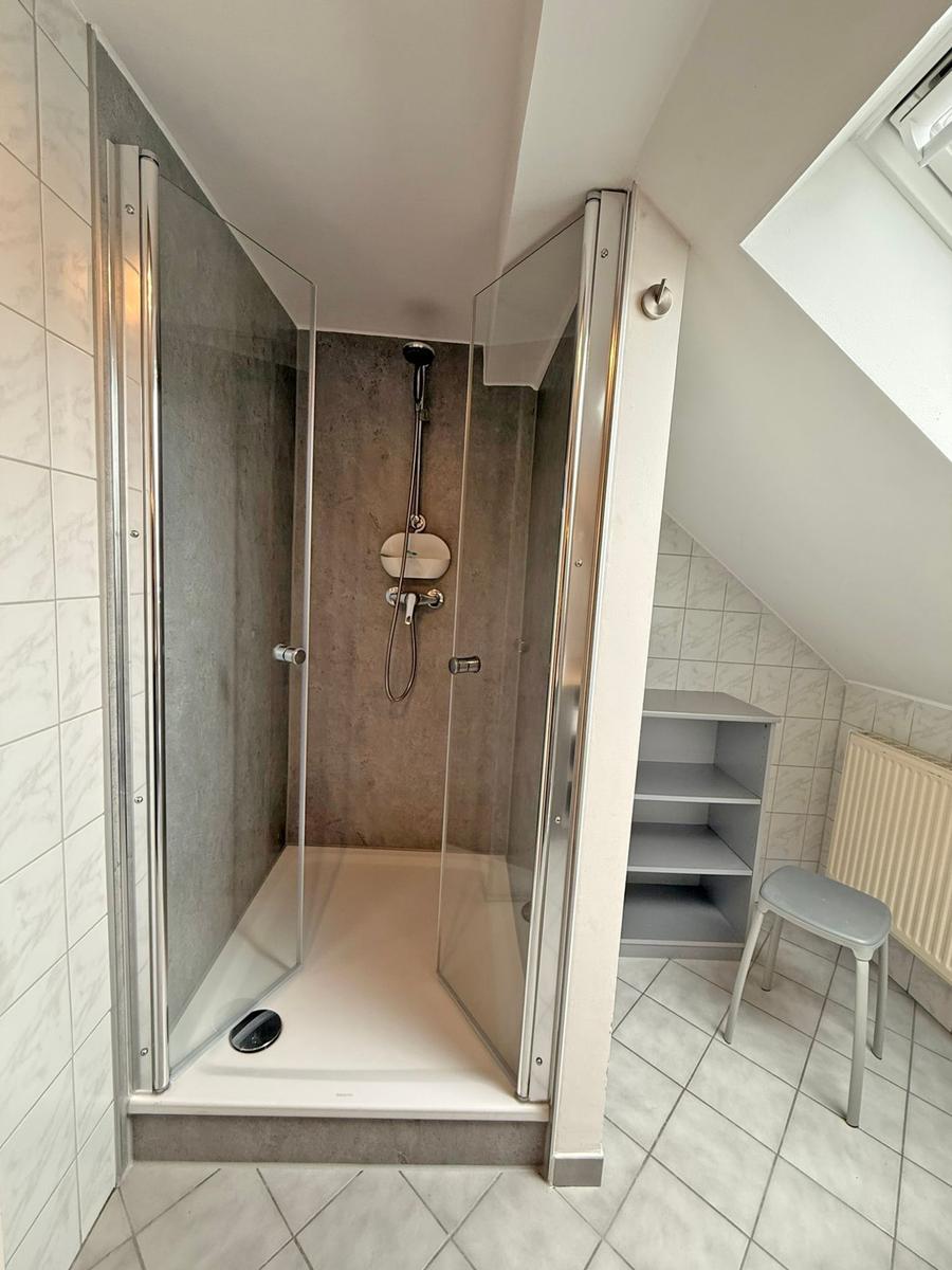 Duschkabine mit Glaswand, Regal und Stuhl in Dachschrägen-Bad