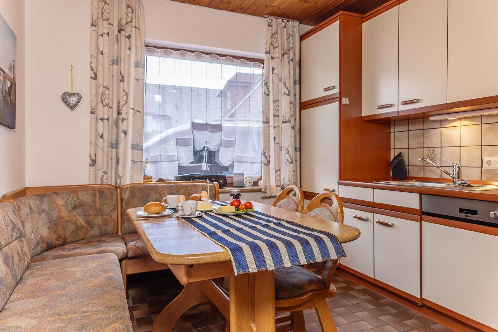 Küche mit Esstisch, Sofa und Fenster. Holzmöbel und Küchenschränke.