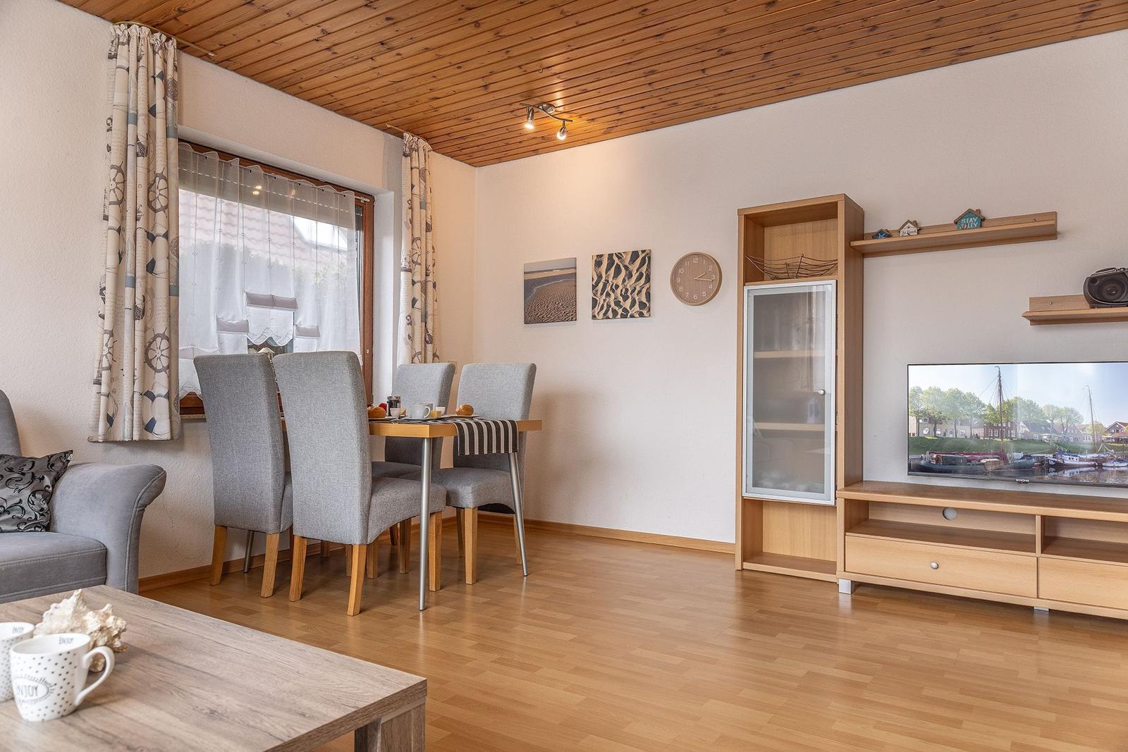 Wohn- und Essbereich mit Holzboden, TV und Essgruppe.