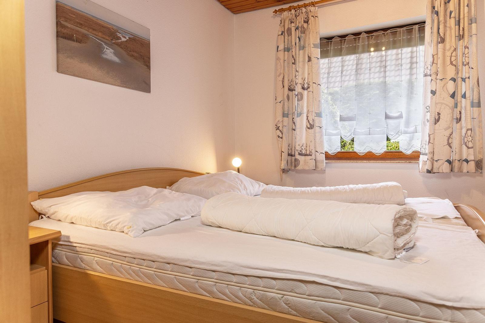 Schlafzimmer mit Bett, Fenster und Wandbild.
