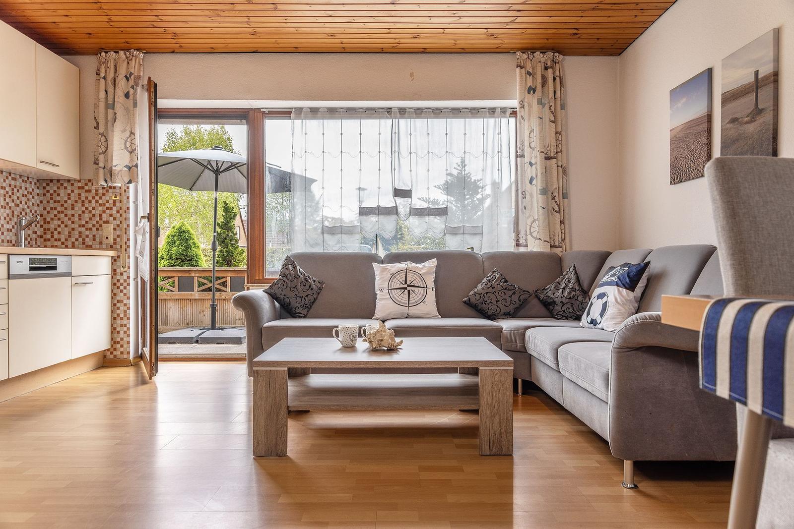 Wohnzimmer mit Sofa, Couchtisch und Blick auf Terrasse mit Sonnenschirm.