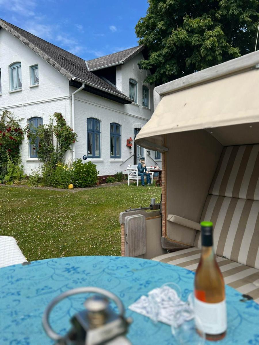 Haus mit Garten, Sonnenschirm und Tisch mit Flasche.