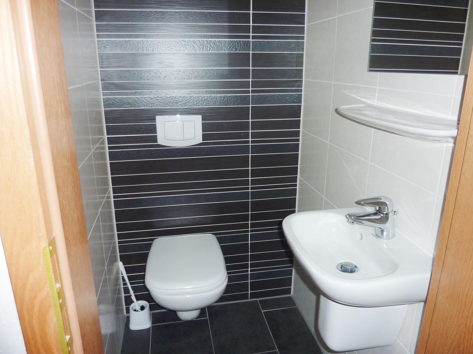 Badezimmer mit Toilette, Waschbecken und schwarz-weißen Fliesen.