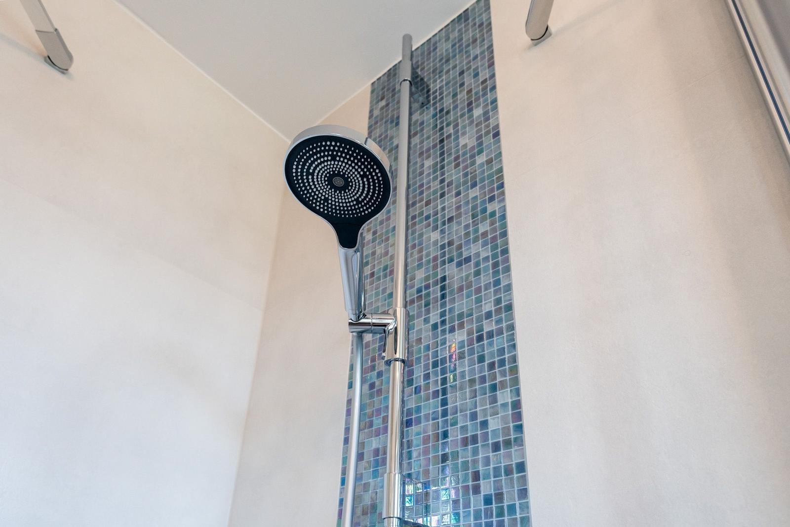 Duschkopf mit Chromarmatur und Mosaikfliesenwand