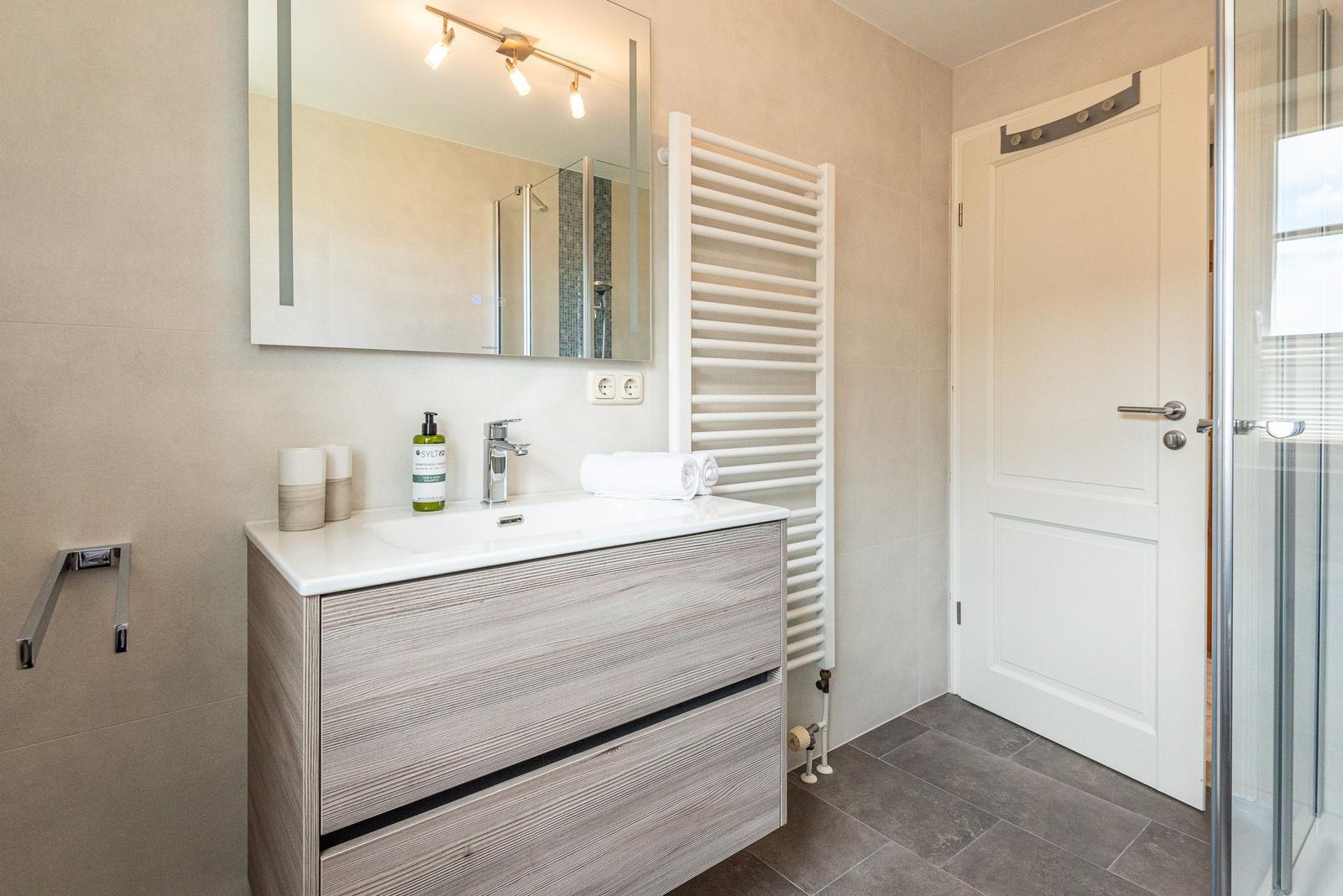 Badezimmer mit Waschtisch, Spiegel und Dusche