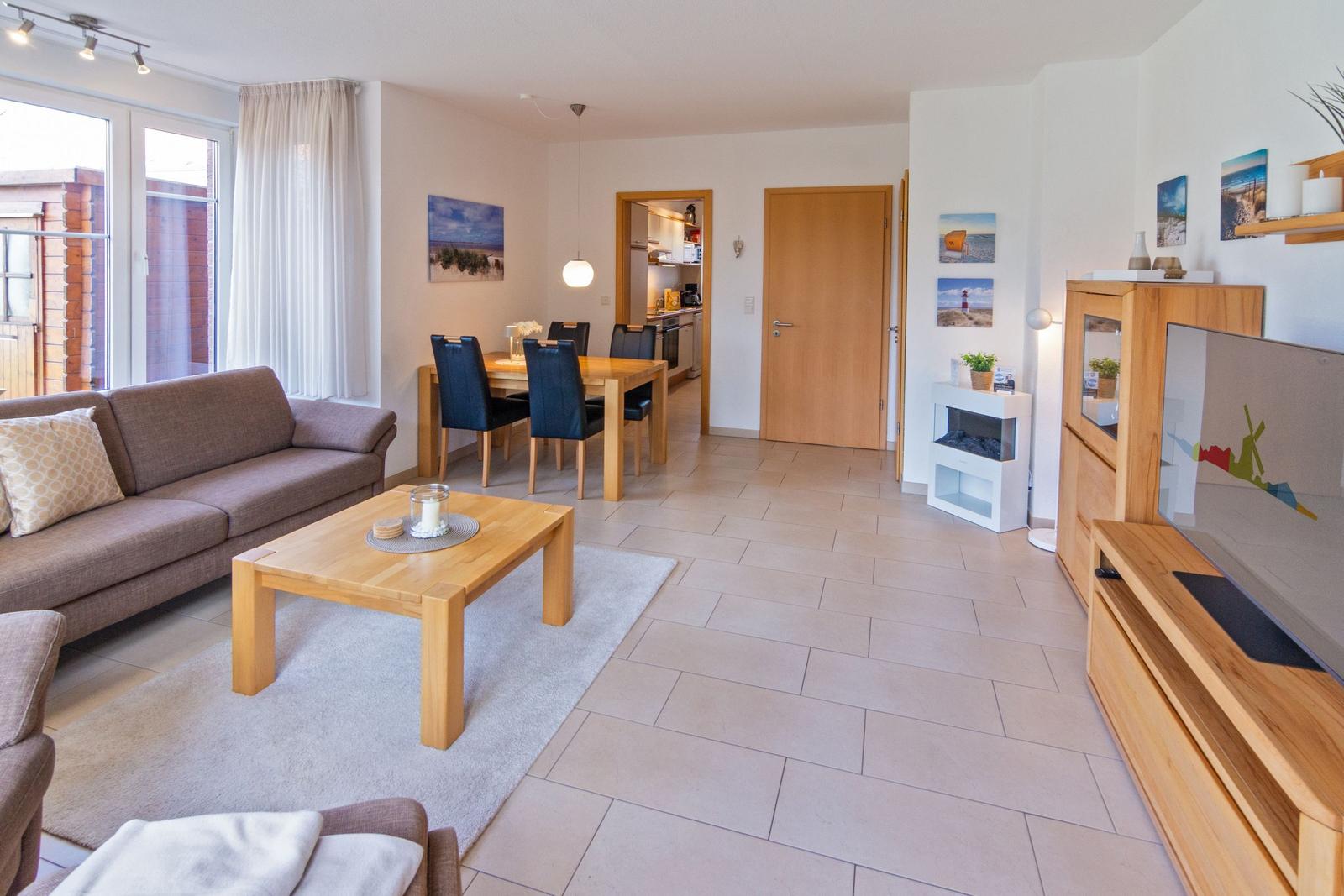 Wohnzimmer mit Sofa, Esstisch und Küche im Hintergrund.