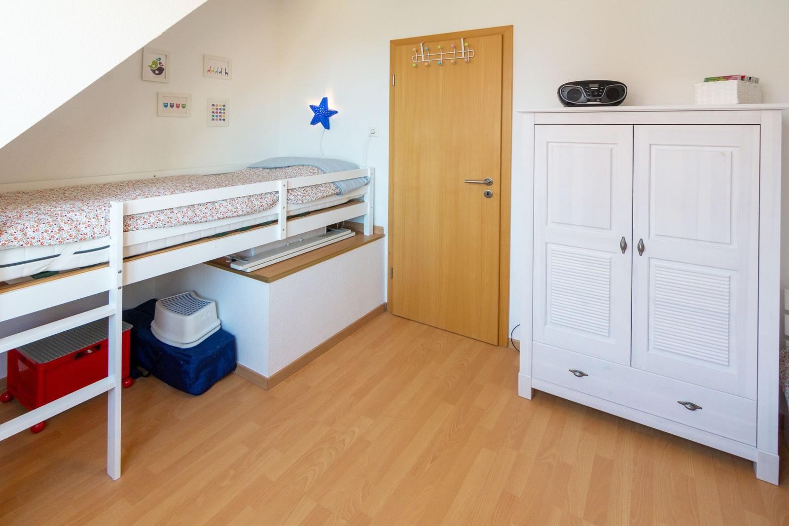 Ein Schlafzimmer mit Doppelstockbett, weißem Schrank und Holzboden.