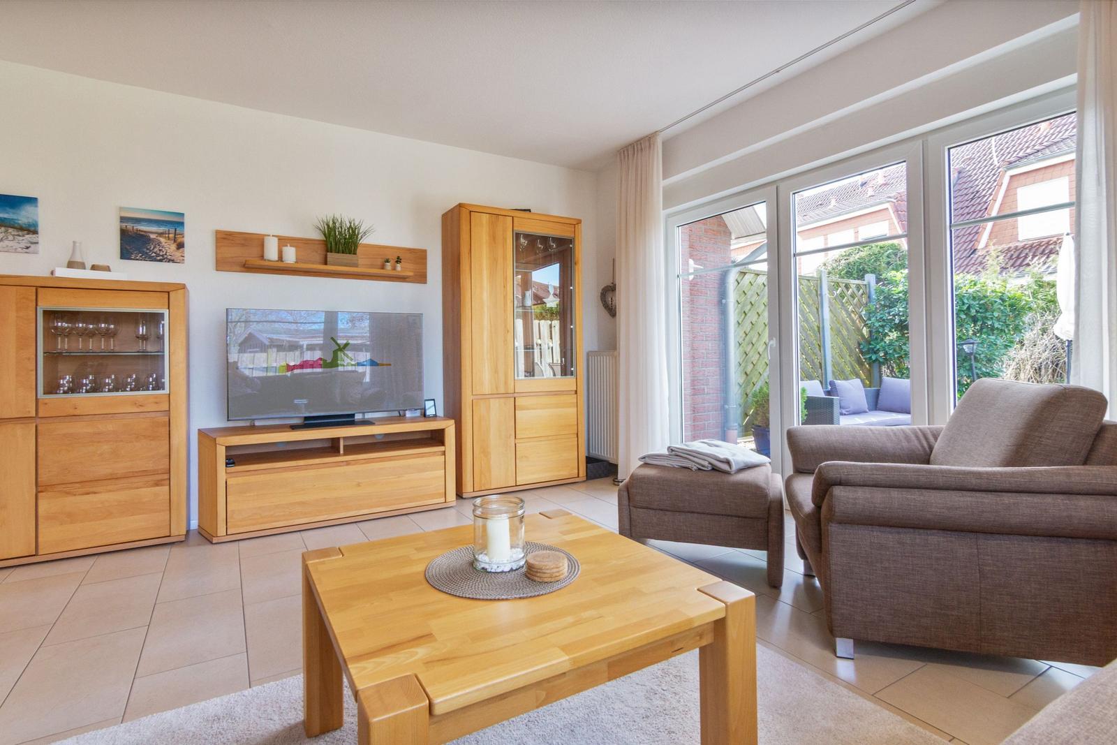 Wohnzimmer mit Holzmöbeln, Fernseher und Blick auf die Terrasse.
