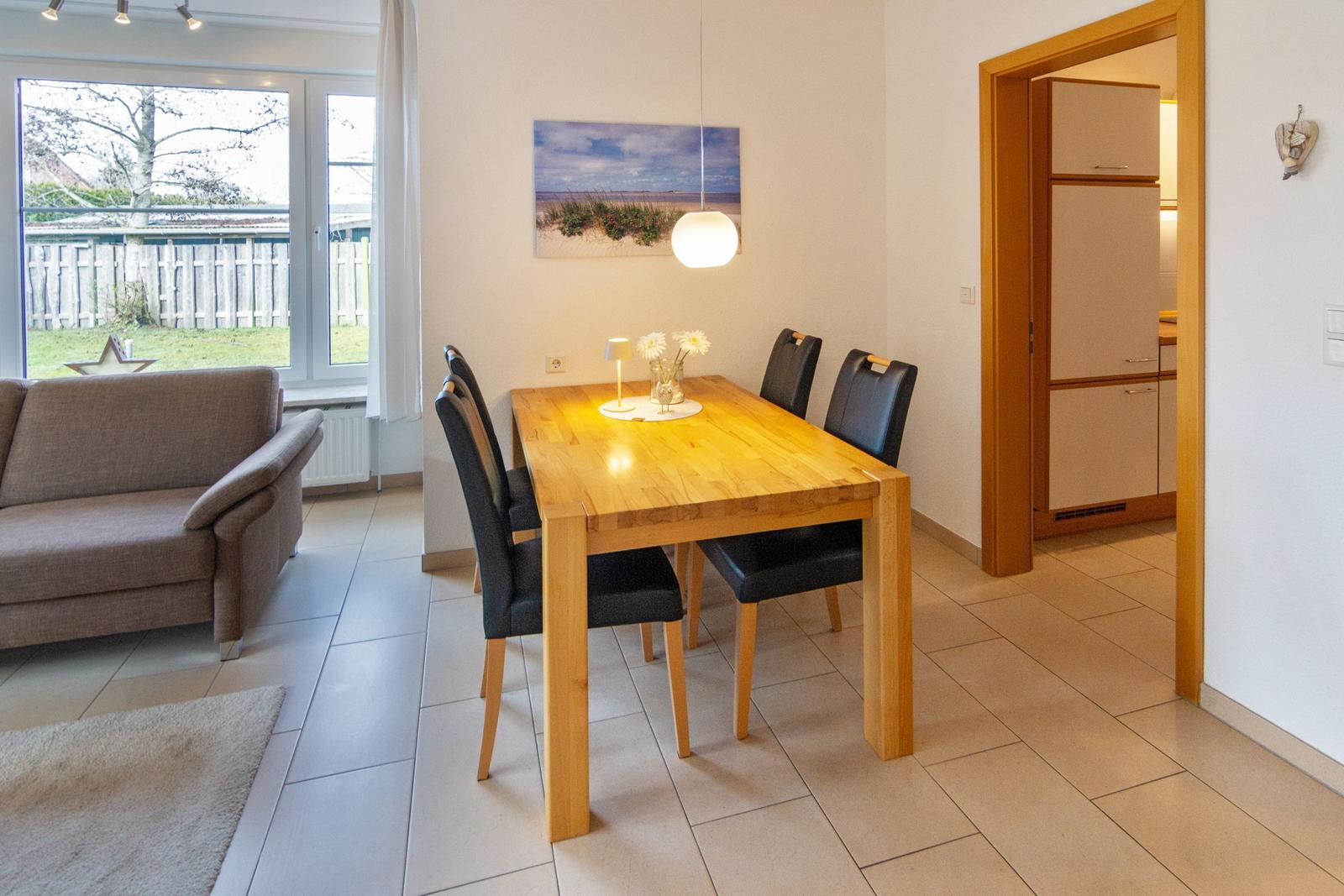 Essbereich mit Holztisch und Stühlen. Durchgang zur Küche. Fenster mit Blick auf Garten.